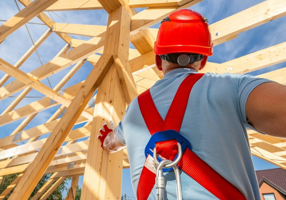 Construction Worker Guiding Framework Assembly at a Building Site Under a Clear Blue Sky
